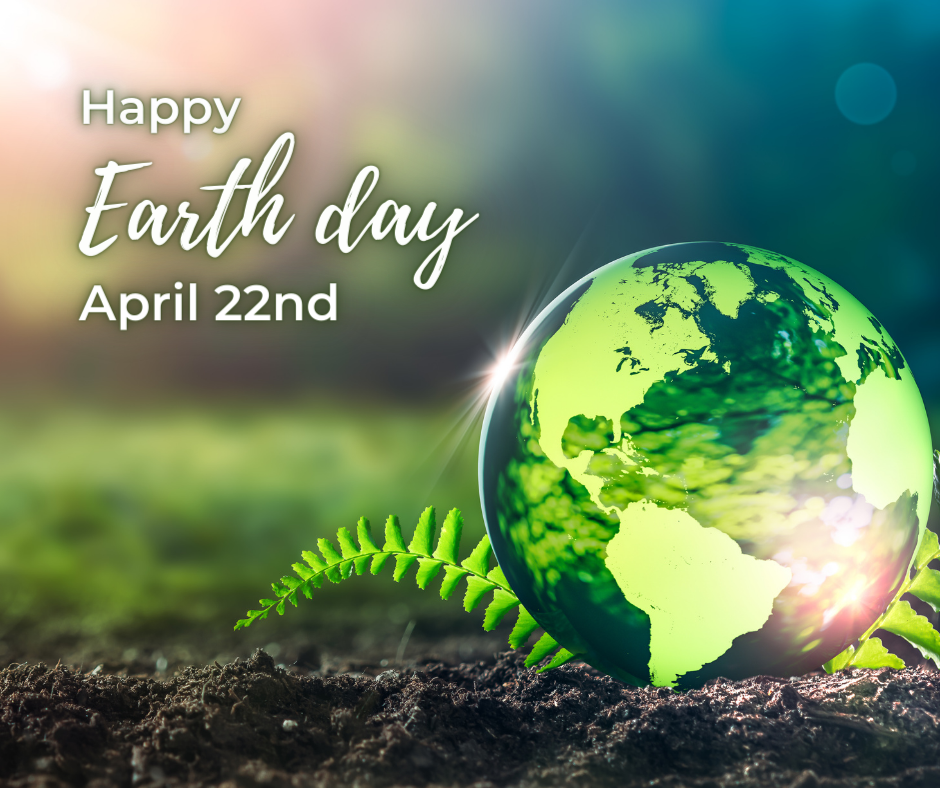 Glowing green marble with N & S America sitting on rich soil and a green fern.  "Happy Earth Day April 22nd."